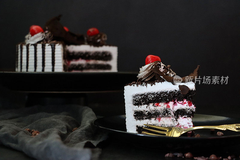 黑森林大门切片的图片，上面有莫雷罗樱桃，豪华的巧克力蛋糕上有奶油，上面覆盖着融化的巧克力，黑色背景，三层