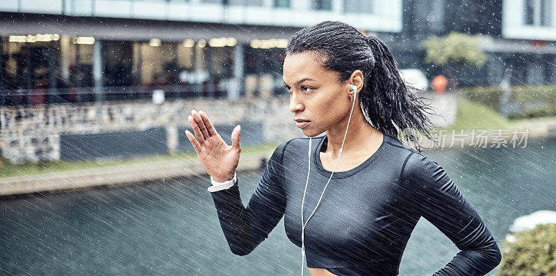 黑人女性，健身和在雨中带着耳机跑步，在城市里运动的动机或决心。非裔美国运动女跑步者做激烈的有氧运动在下雨的天气
