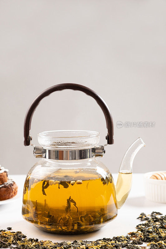 米色背景的玻璃茶壶里盛着橙皮绿茶