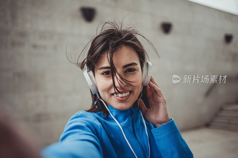 一位美丽的黑发年轻女子在训练结束后休息，她穿着运动服，正在为社交网络自拍