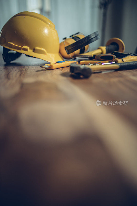木桌上有建筑工具和一顶黄色头盔