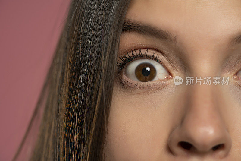 年轻女子睁大的棕色眼睛:表示惊讶和近距离观察