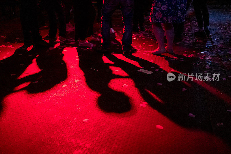 跳舞的人的影子出现在舞池的红光中