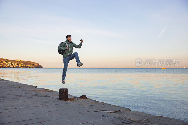 清晨，兴奋的男游客在海边跳跃