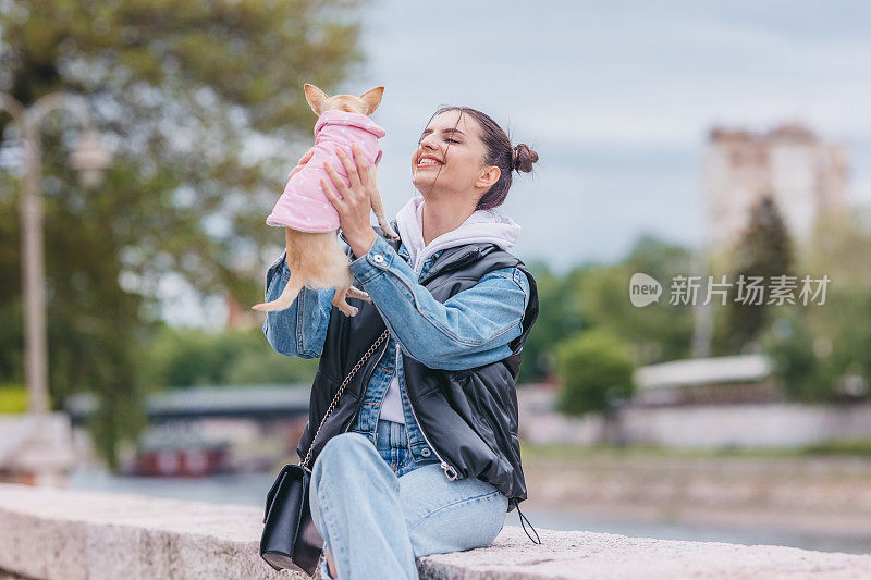 漂亮的年轻女子和可爱的小狗吉娃娃在河边