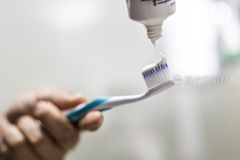 女性用手把牙膏涂在牙刷上