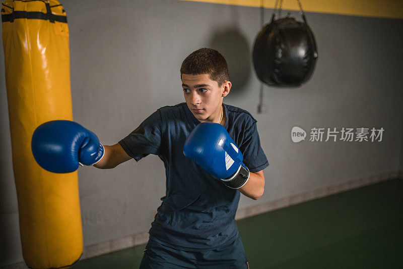 一个年轻的男运动员在拳击馆训练，专注于变得更强壮