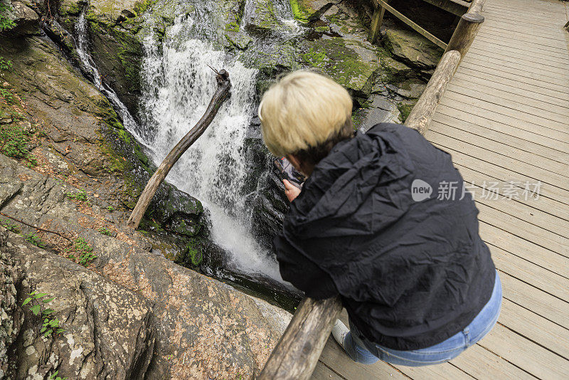 金发女郎从宾夕法尼亚州的桥上拍摄布什基尔瀑布。瀑布地标是宾夕法尼亚州波科诺斯山脉最受欢迎的景点。