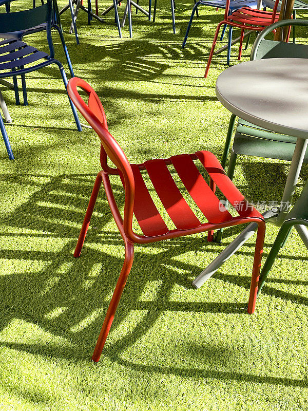 现代现代户外用餐区特写形象，金属桌椅，市中心人造草坪，绿色人造草皮，重点放在前景
