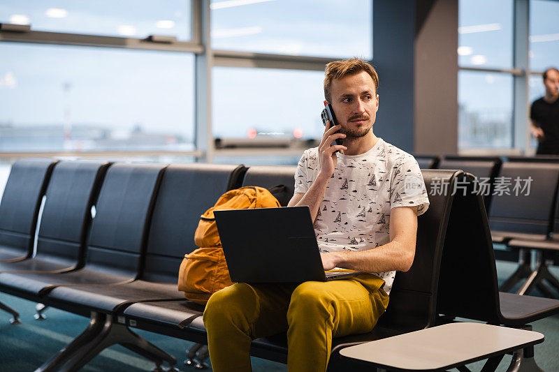 年轻的男性游客在机场候机时使用笔记本电脑