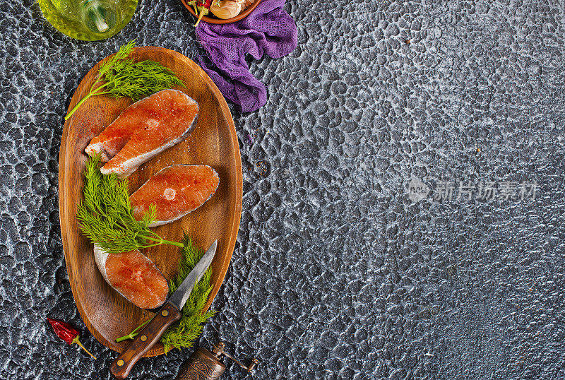 新鲜鲑鱼排准备烹饪的生鱼。黑色石板桌的俯视图。