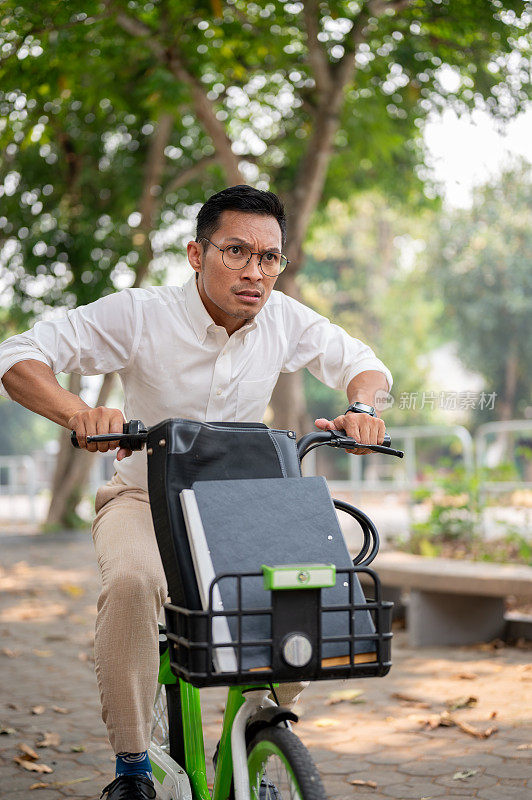 一个焦虑的亚洲商人早上骑着自行车赶着去上班。