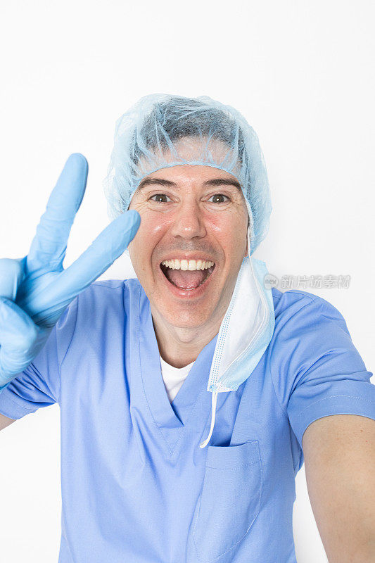 医生在自拍中微笑并做出胜利的手势。成功的手术。