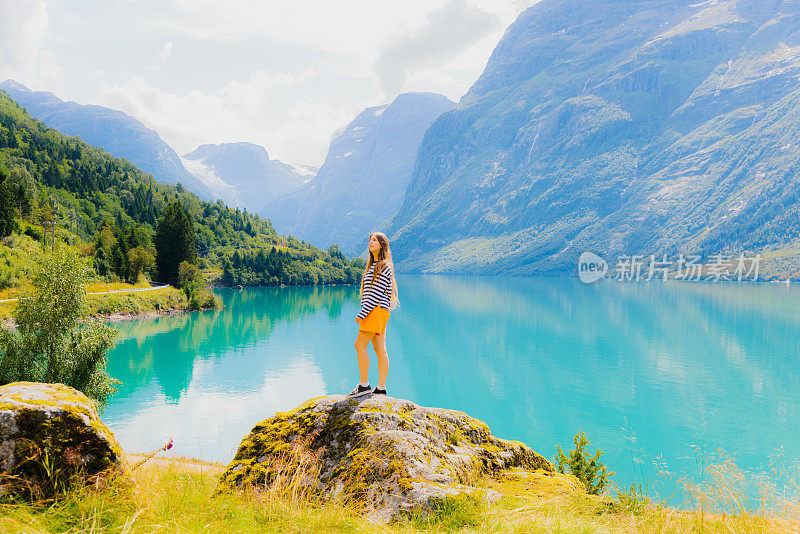 女游客在挪威洛瓦内特冰川山湖观赏田园诗般的风景