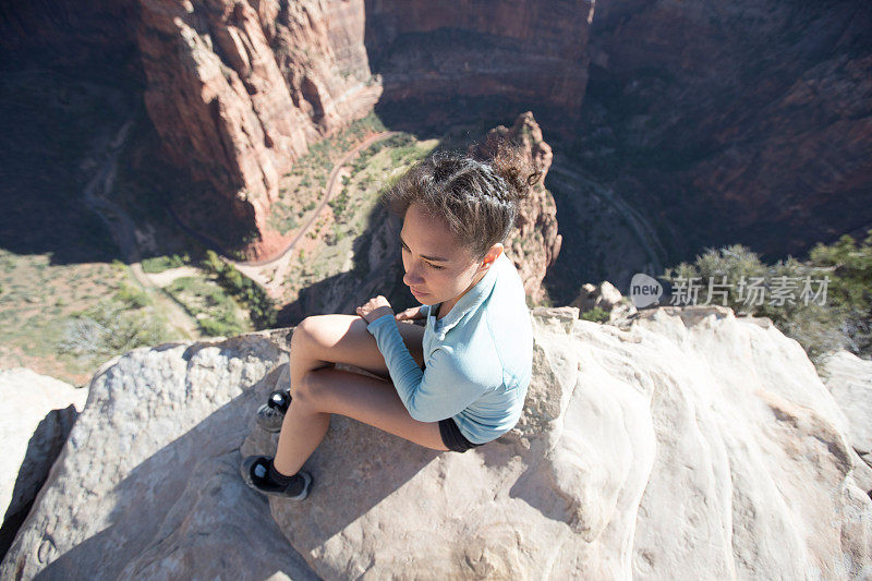 一位女性徒步旅行者在犹他州的悬崖边上休息