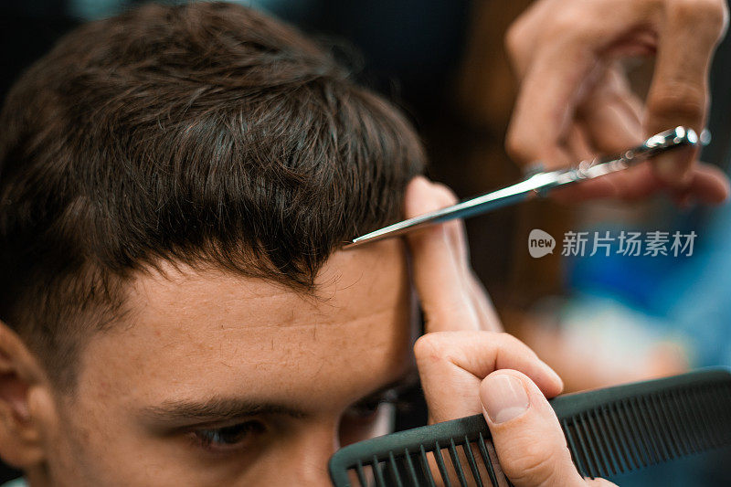理发店。男人理发的特写，师傅在理发店里做发型。特写，大师理发师做的发型和造型与剪刀。理发店的概念。