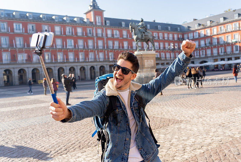有吸引力的年轻白人旅游学生男子玩得开心，兴奋地用智能手机自拍，马德里，西班牙。旅游，度假，环游欧洲的概念。