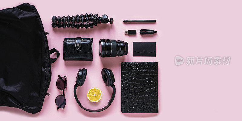 现代黑色配件，小玩意和柠檬片在粉红色的背景，俯视图