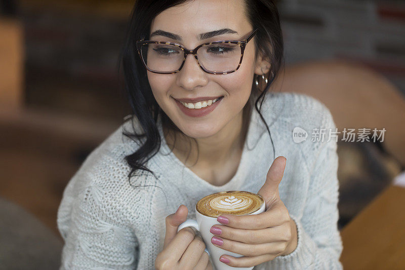 可爱的年轻女子在咖啡馆喝咖啡