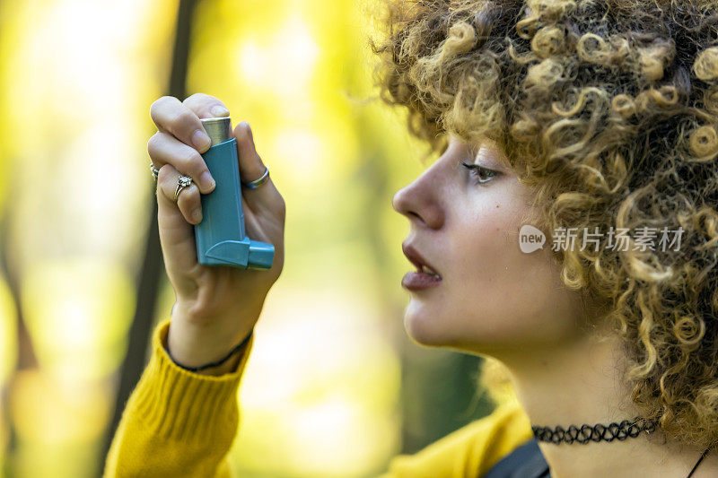 在树林里使用吸入器的女性徒步旅行者。年轻女性用吸入器治疗哮喘