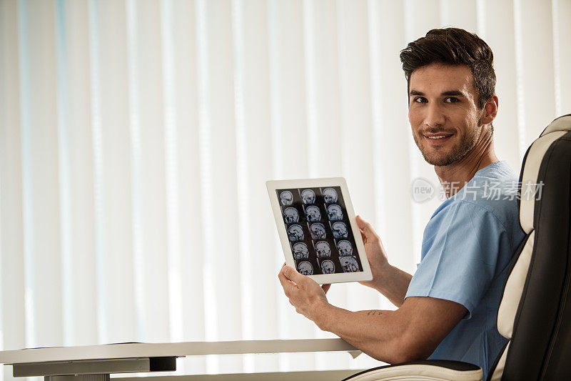 神经外科医生拿着一个数字平板电脑屏幕上显示着脑瘤的核磁共振扫描结果