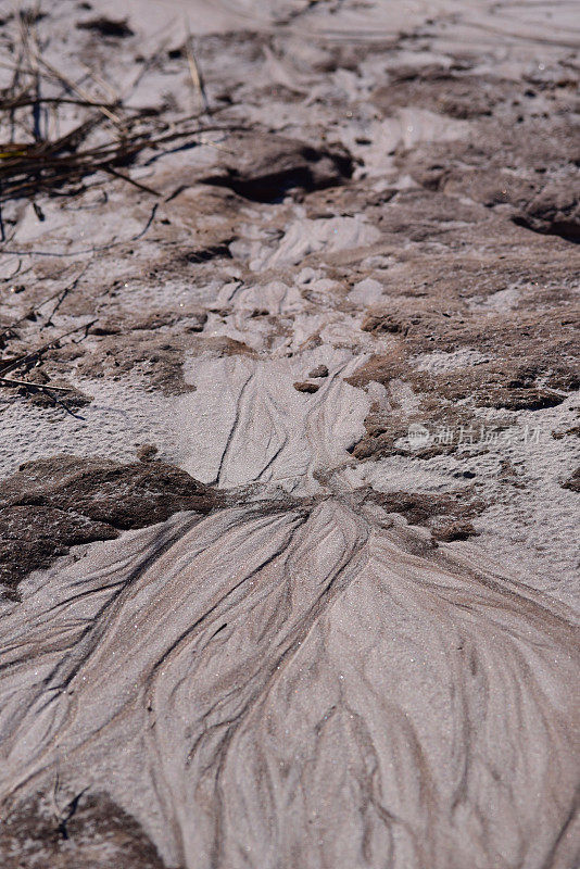 被侵蚀的沙子呈米黄色和棕色，在粗糙的区域有水滴
