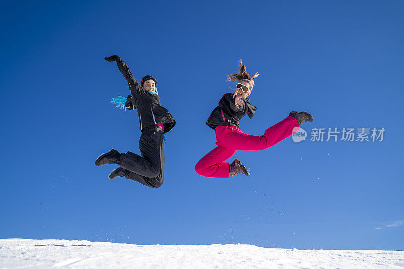 年轻的滑雪者在雪山上嬉戏跳跃