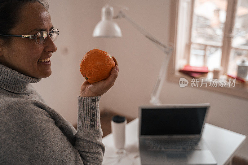 健康的生活是一种精神状态。年轻的专业建筑师在共享的办公空间工作。在休息时间吃橘子。