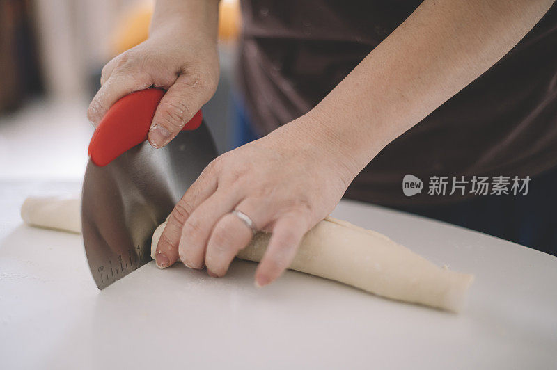 一位亚裔华人家庭主妇正在准备食物，切面粉和鸡蛋，在桌子上做面团