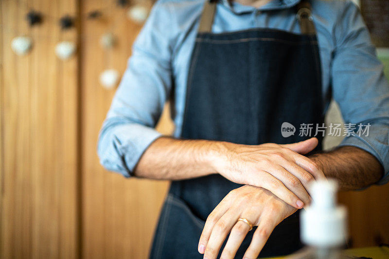 企业家使用酒精凝胶清洁和洗手在他的小公司