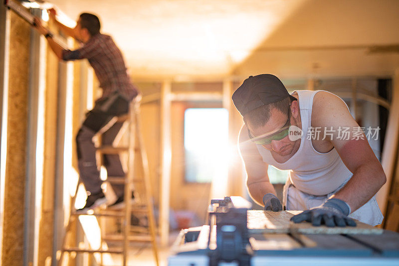 建筑工人在工地用圆锯切木板。
