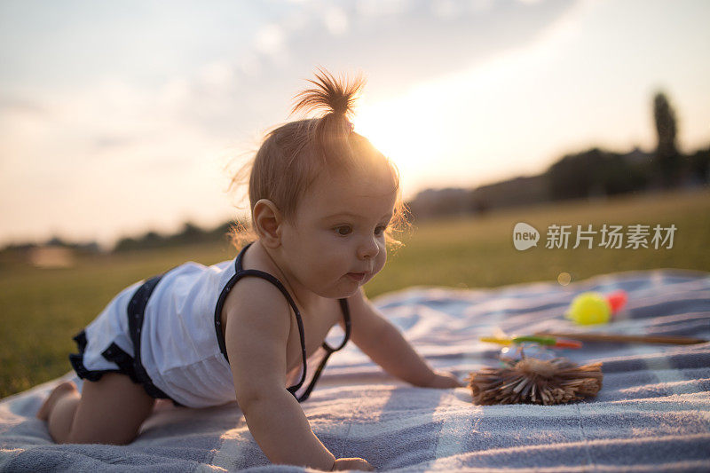 夏天的一天，小女孩在公园的毯子上爬行