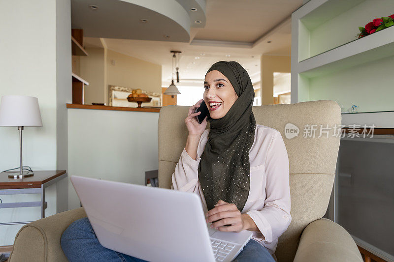 穆斯林年轻女子在家中扶手椅上使用笔记本电脑