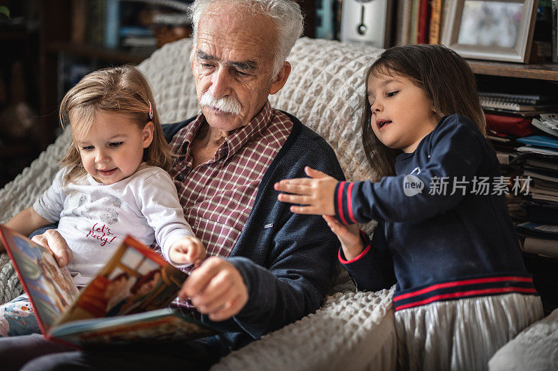可爱的小女孩和爷爷一起读儿童读物