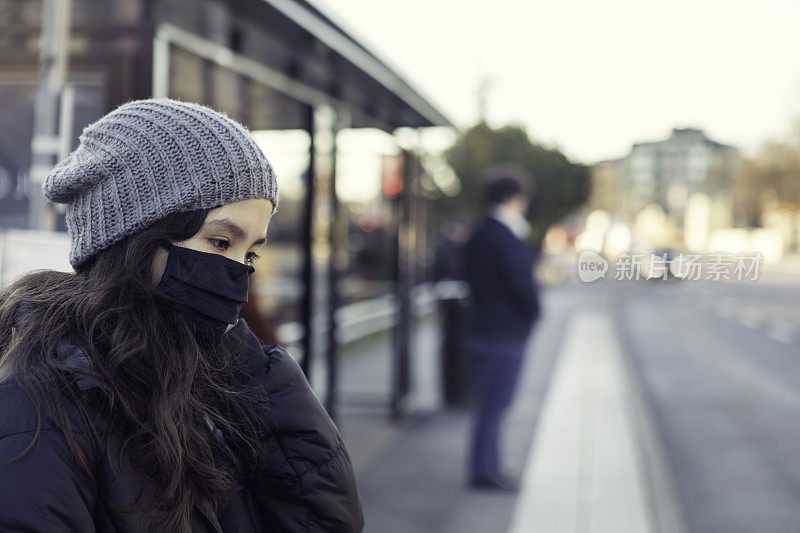 一个女孩在公共汽车站戴着防护口罩