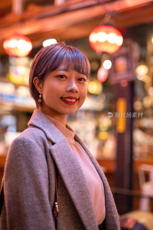 日本“居酒屋”酒吧街的年轻女子画像