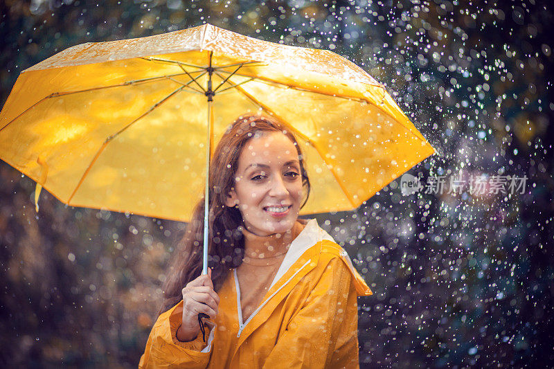 秋雨中带着透明塑料伞的快乐女人