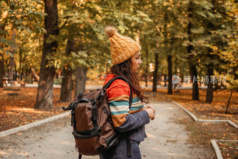 秋天旅行，秋天旅行，度假，独自旅行。秋季公园里背着双肩包的大号女孩