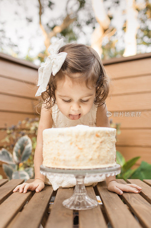 在新冠肺炎期间，小女孩在家的2岁生日派对上尝试她的简单奶油生日蛋糕