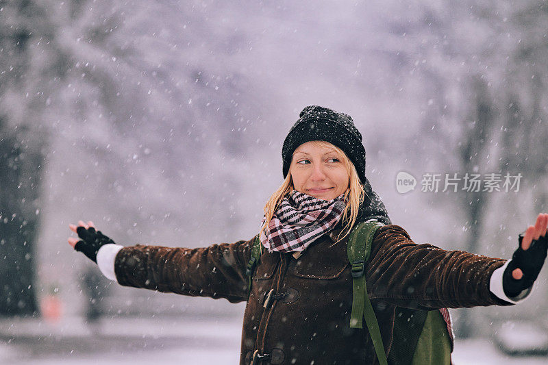 美丽的女人举起双手，享受在寒冷的雪天