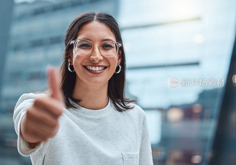 一个年轻的女商人在城市背景下竖起大拇指的照片