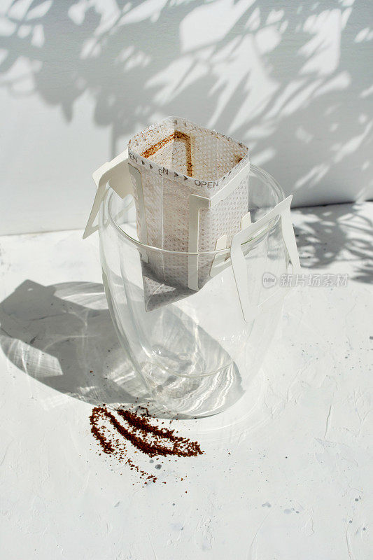 玻璃杯滴咖啡袋白色背景与阴影和复制空间。打开即时纸袋。