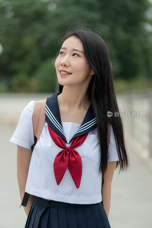 年轻的亚洲女性穿着学生服装，在大学里