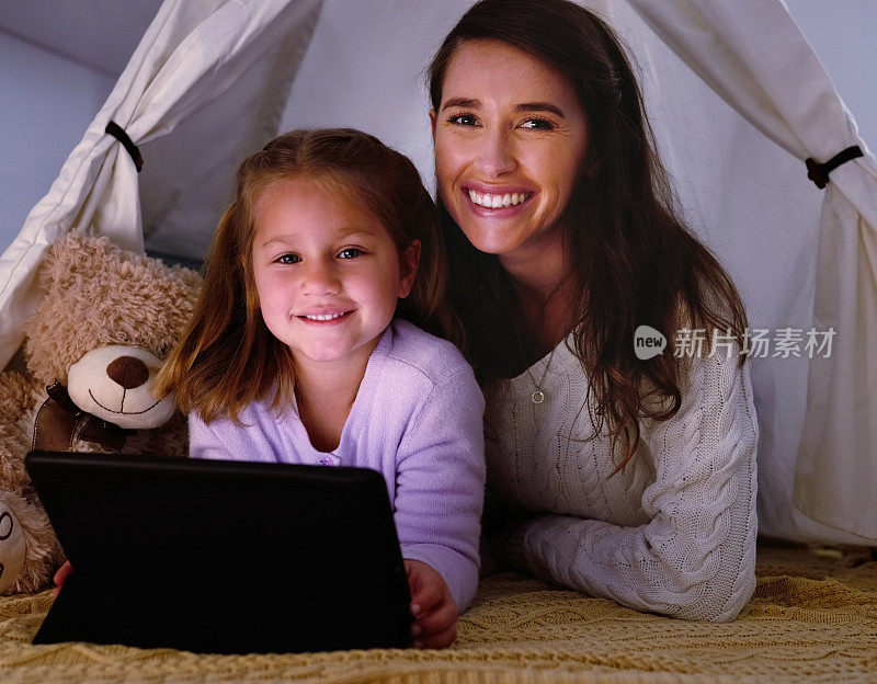 一个小女孩和她的母亲在晚上看一个数码平板电脑