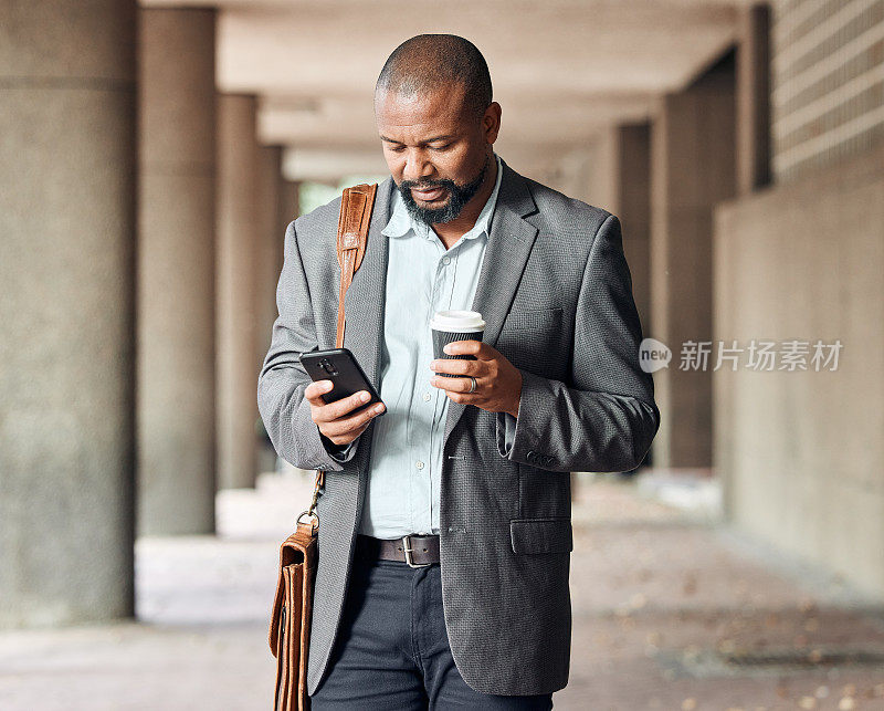 一名成熟的商人一边喝咖啡一边用智能手机发短信