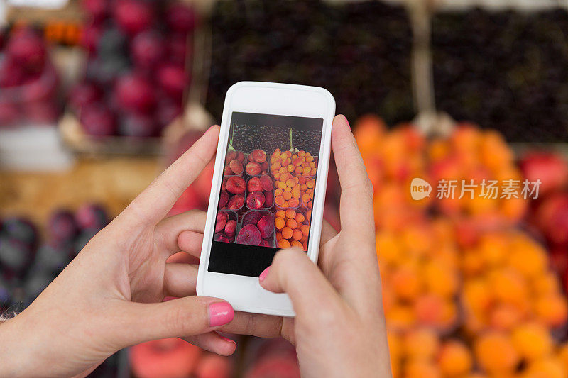 手与智能手机拍照的水果