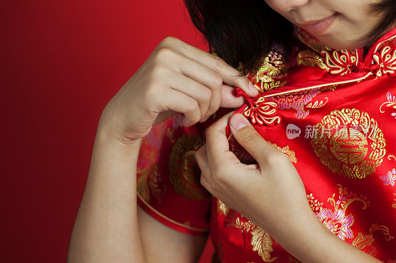 近距离亚洲妇女的手在旗袍上的红色背景。