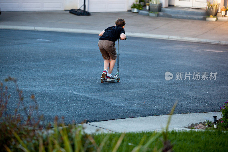 一个小男孩骑着滑板车