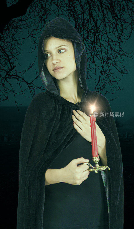 寡妇女巫在黑色的头巾和点燃的蜡烛