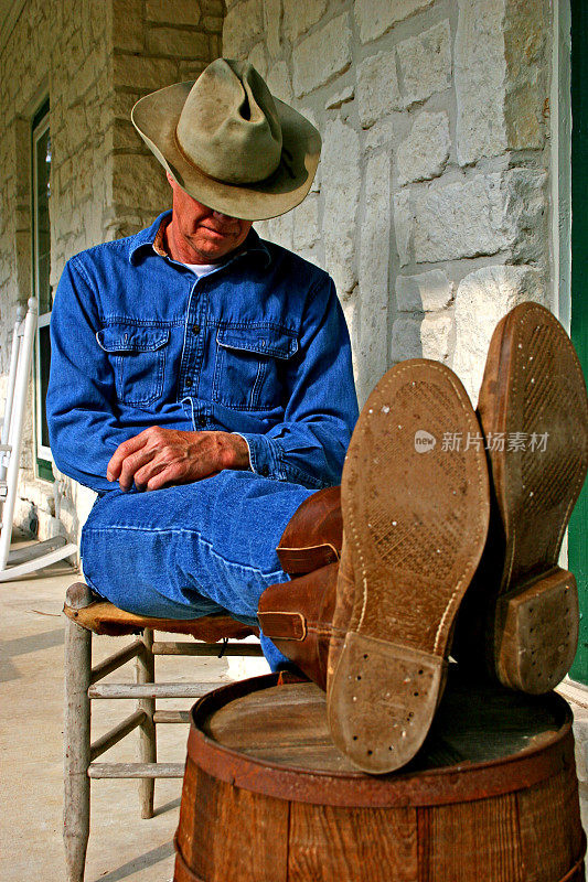 在前廊打盹的牛仔。农舍。靴,帽子。桶,乡村。